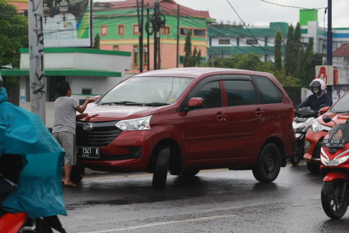 Seorang perempuan menahan mobil yang tengah melaju
