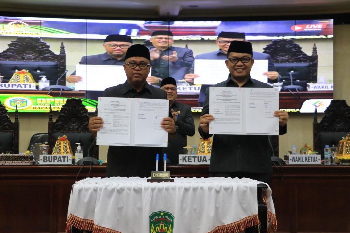 BERITA ACARA -- Bupati Luwu Timur, H Budiman dan Ketua DPRD Lutim, Aripin memperlihatkan naskah Ranperda disaksikan Wakil Ketua, H Usman Sadik dan seluruh yang hadir usai menandatangani berita acara persetujuan bersama atas Ranperda APBD Tahun 2024.