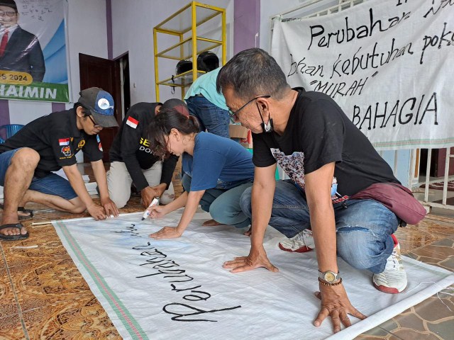 IST MEMBUAT SPANDUK--Relawan Mileanies Kota Makassar membuat spanduk rakyat dengan bahan dari karung bekas 