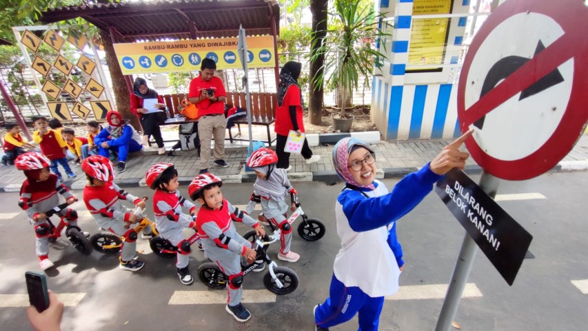 APRESIASI -- Salah seorang guru PAUD sedang mengajarkan rambu-rambu lalulintas kepada sejumlah anak didik PAUD langsung di lapangan.