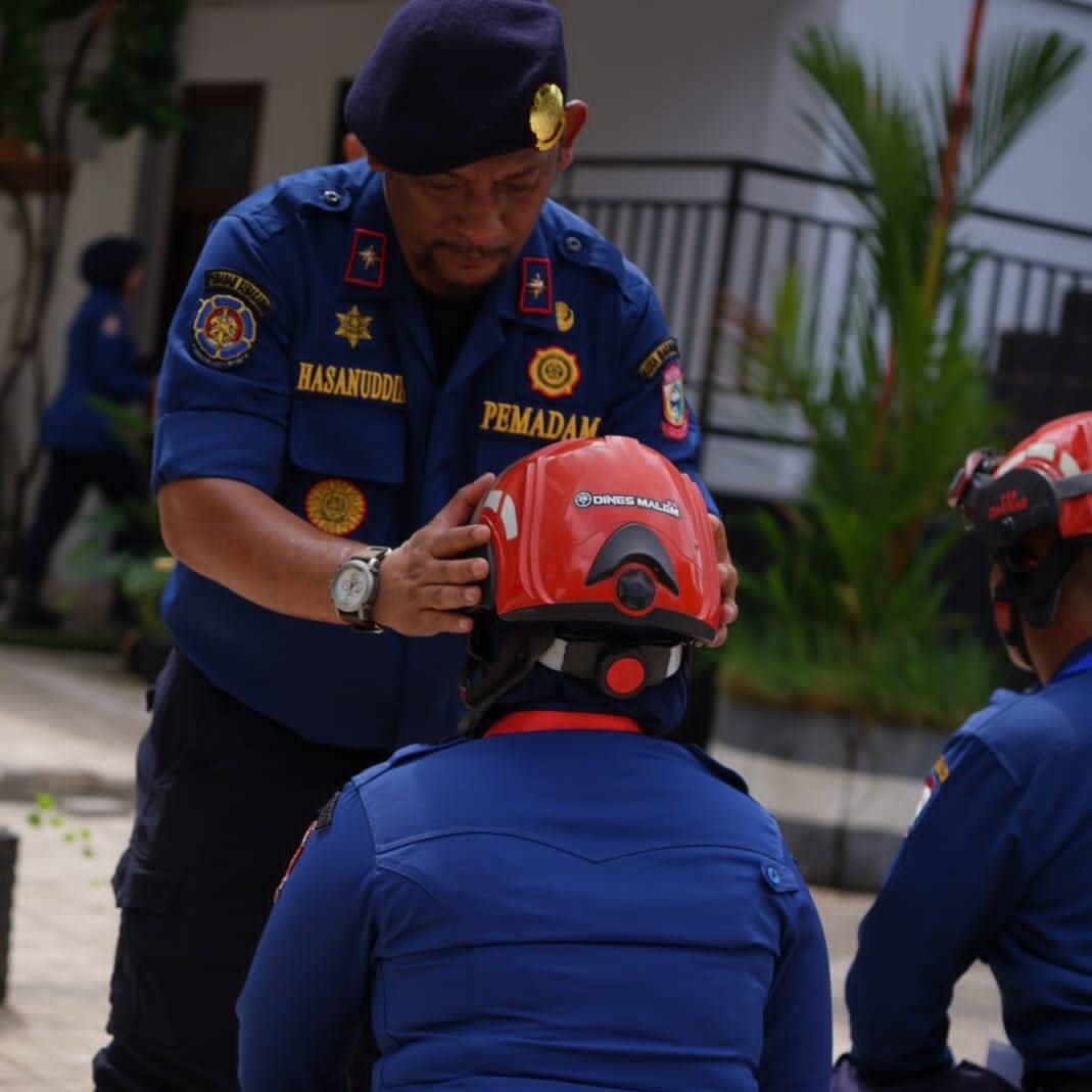 ist PELATIHAN--Kadis Damkar Kota Makassar, Hasanuddin memasangkan helm ke personel damkar saat membuka kegiatan Pendidikan dan Pelatihan Pemadam Kebakaran Program 70 Jam Pelajaran (JP) yang berlangsung di Mako Damkar Makassar mulai Senin 4 – 10 Desember.