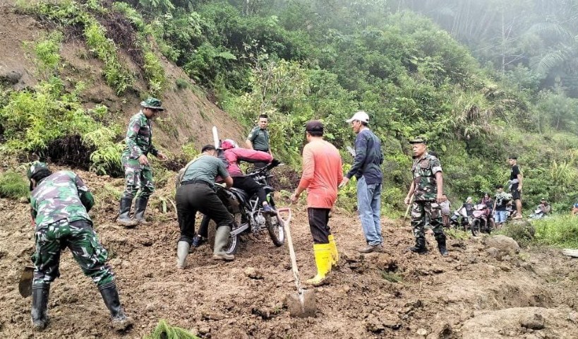 BANTU WARGA -- Prajurit TNI dari Koramil Rantepao turun lokasi bencana untuk membantu warga melintasi jalan yang berlumpur gegara terjadinya longsor pada Rabu (10/1) lalu.