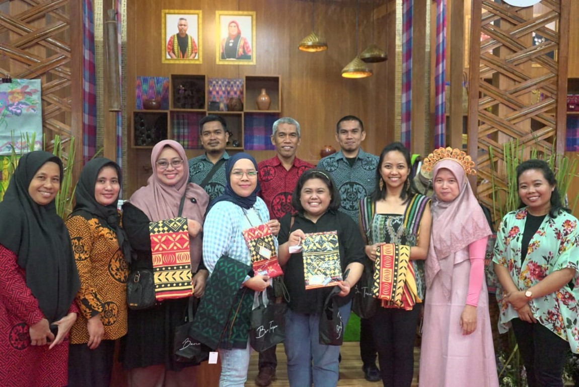 LARIS MANIS -- Ketua Harian Dekranasda Lutim sekaligus Kepala Disdagkop-UKMP, Senfry Oktavianus foto bersama para pengunjung sembari memegang kain Taipa yang  laris manis selama pameran Inacraft) di Plenary Hall JCC, Minggu (3/3).