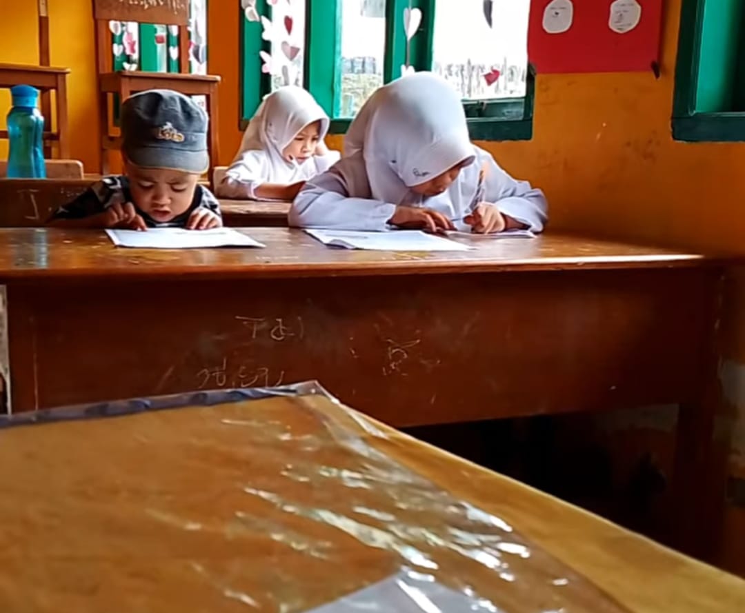 VIRAL -- Bocah berusia sembilan tahun Nuraeni membawa adiknya ke dalam kelas untuk mengikuti proses belajar mengajar. Tampak pula rombongan Kadis Pendidikan Sinjai saat bertandang di rumah Nuraeni membawa adiknya ke dalam kelas untuk mengikuti proses belajar mengajar.
