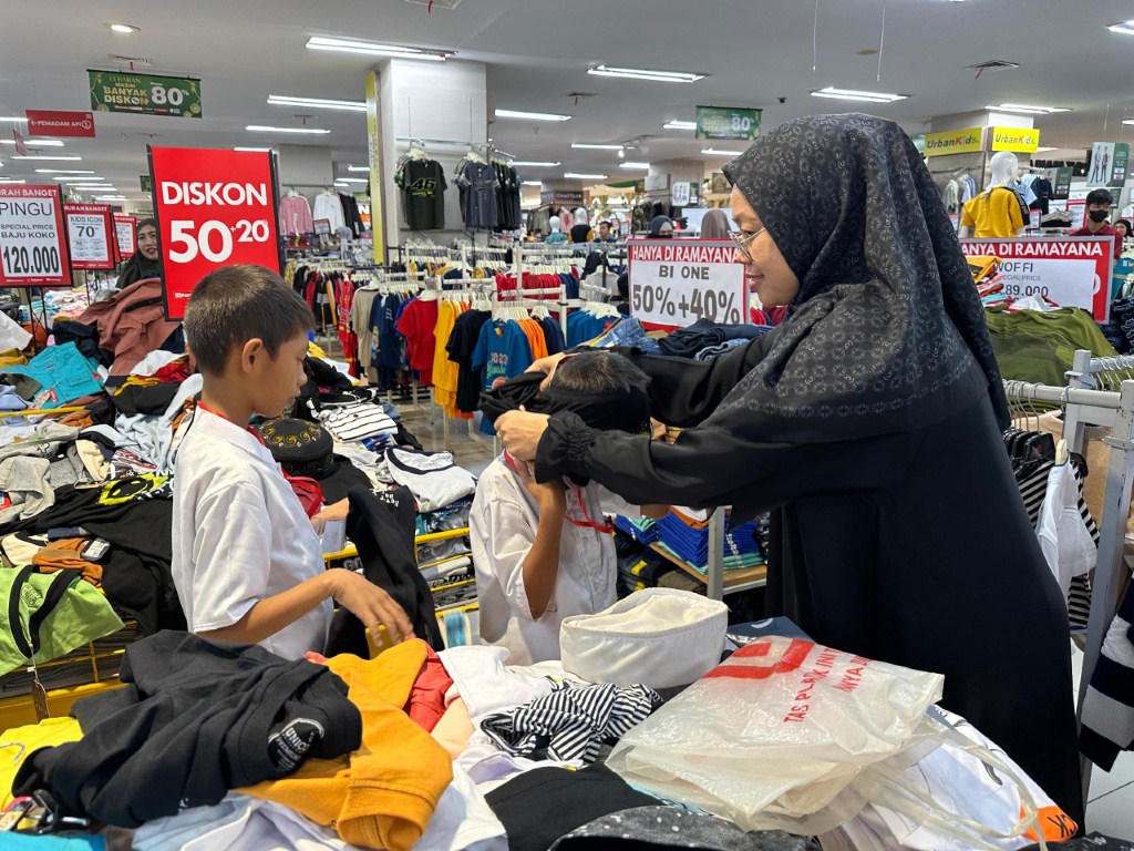 BAJU LEBARAN -- Dua orang anak yatim dan dhuafa tampak begitu bahagia memilih baju lebaran didampingi relawan pendamping dari YBM PLN UID Sulselrabar.