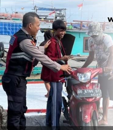IST MEMBANTU -- Salah seorang anggota Polsek Paotere Polres Pelabuhan Makassar membantu warga Kepulauan Sangkarrang yang menurunkan motornya dari kapal saat tiba di Pelabuhan Paotere.
