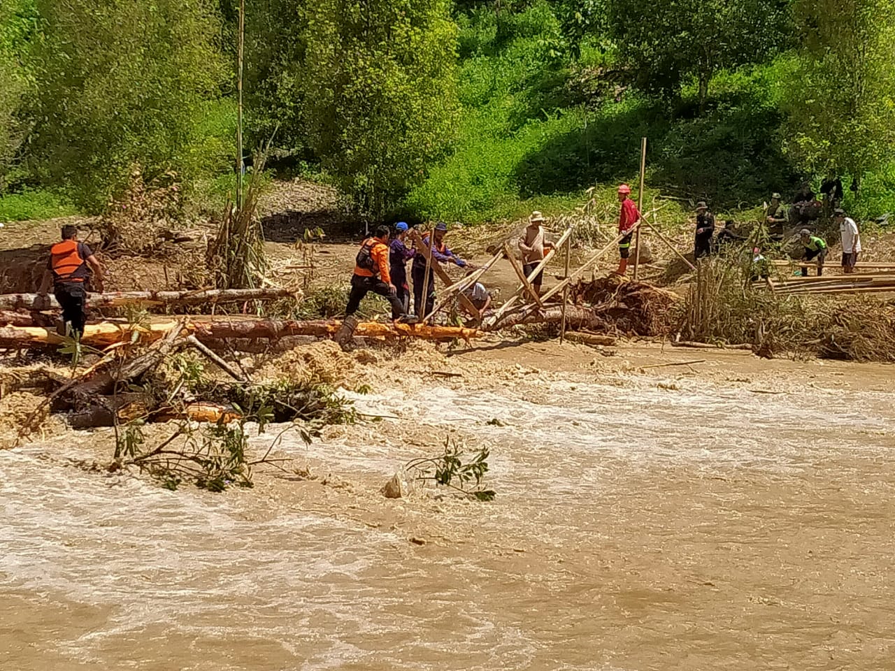 IST TERPUTUS-Salah satu akses penghubung di Desa Kadundung, Kecamatan Latimojong, Kabupaten Kuwu mengalami kerusakan parah sampai terputus karena derasnya arus pada saat bencana banjir melanda. Tim Penyelamatan dari Dinas Damkarmat Kota Makassar bekerja sama Tim SAR di lokasi segera membangun jembatan darurat untuk mempermudah akses evakuasi dan pendistribusian bantuan logistik.