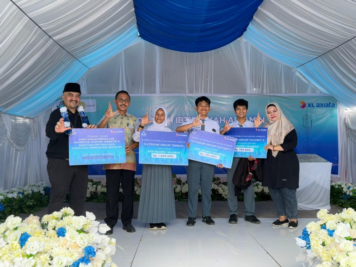 XL AXIATA BAIK -- Chief of Human Capital Officer XL Axiata, M Hira Kurnia (kiri) dan Human Capital Expert XL Axiata, Retno Wulan (paling kanan), menyerahkan hadiah lomba program XL Axiata Baik ke siswa SMAN 1 Baubau bersamaan dengan peresmian proyek pembangunan Madrasah Ibtidaiyah dan sarana pendukungnya di Kabupaten Buton Tengah, Sulawesi Tenggara, Jumat (24/5).