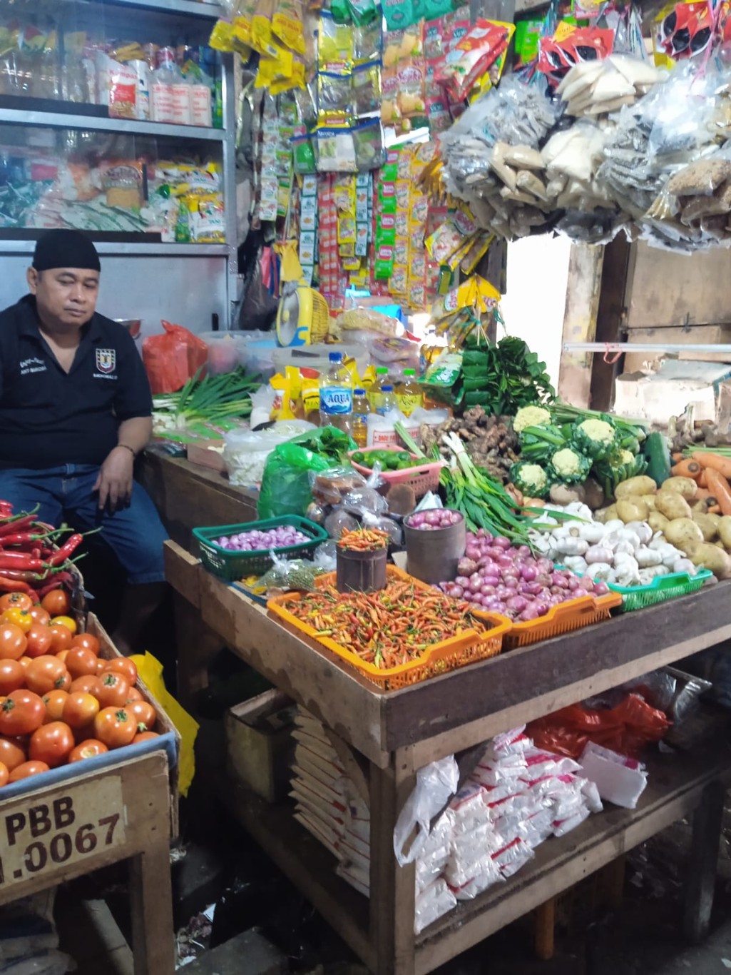 BKM/YUSRIL HARGA--Harga kebutuhan pokok jelang Iduladha masih tetap stabil, bahkan ada beberapa harga bumbu dapur yang mengalami penurunan termasuk tomat.Tampak Basri saat berada di warungnya.