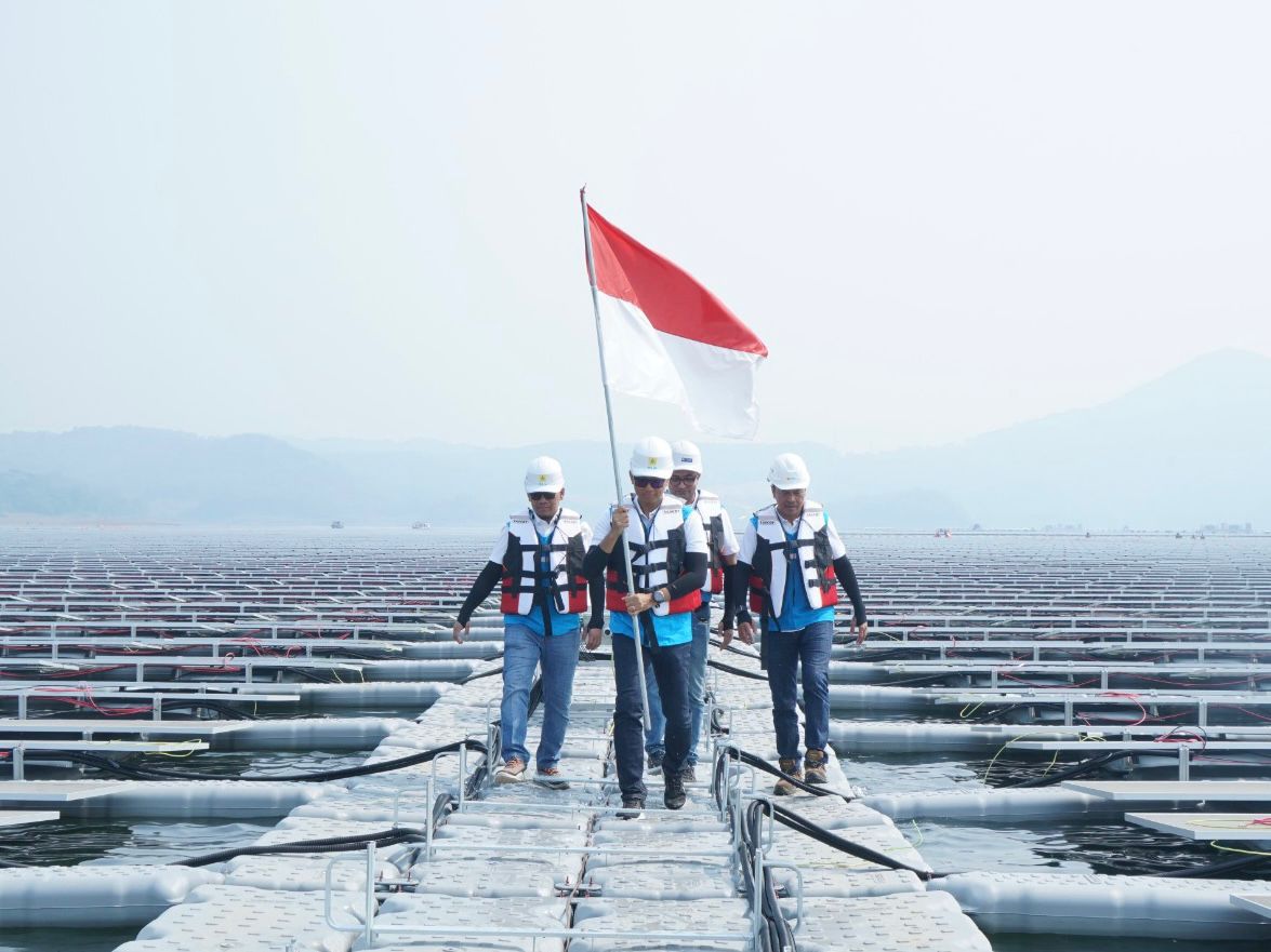PASANG BENDERA -- Direktur Utama PLN, Darmawan Prasodjo (kedua dari kiri) didampingi Direktur Manajemen Pembangkitan PLN Adi Lumakso (kiri), Direktur Utama PLN Nusantara Power, Ruly Firmansyah (kanan), dan Managing Director Masdar Asia Pacific, Sujit S. Parhar (kedua dari kanan), berjalan di antara panel surya untuk memasang bendera merah putih saat meninjau Pembangkit Listrik Tenaga Surya Terapung Cirata di Purwakarta, Jawa Barat.