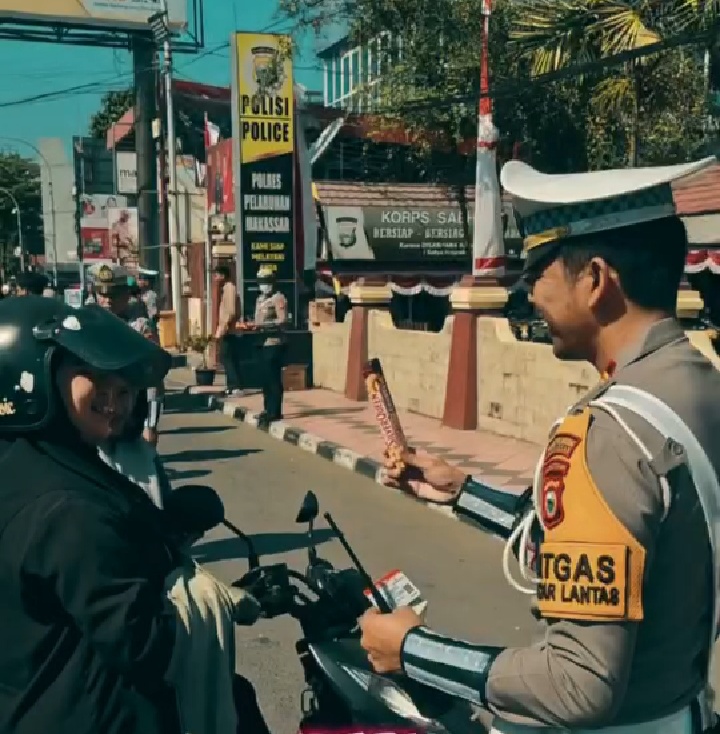 IST OPERASI PATUH -- Kasat Lantas Polres Pelabuhan Makassar membagikan coklat kepada pengendara sepeda motor.