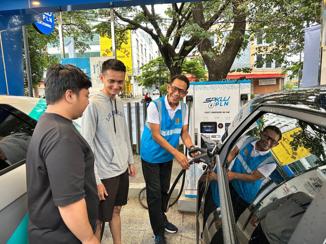 PENGISIAN -- General Manager PLN UID Sulselrabar, Moch. Andy Adchaminoerdin (kanan) membantu pemilik mobil listrik untuk mengisi daya di SPKLU PLN Makassar Selatan, beberapa hari lalu.