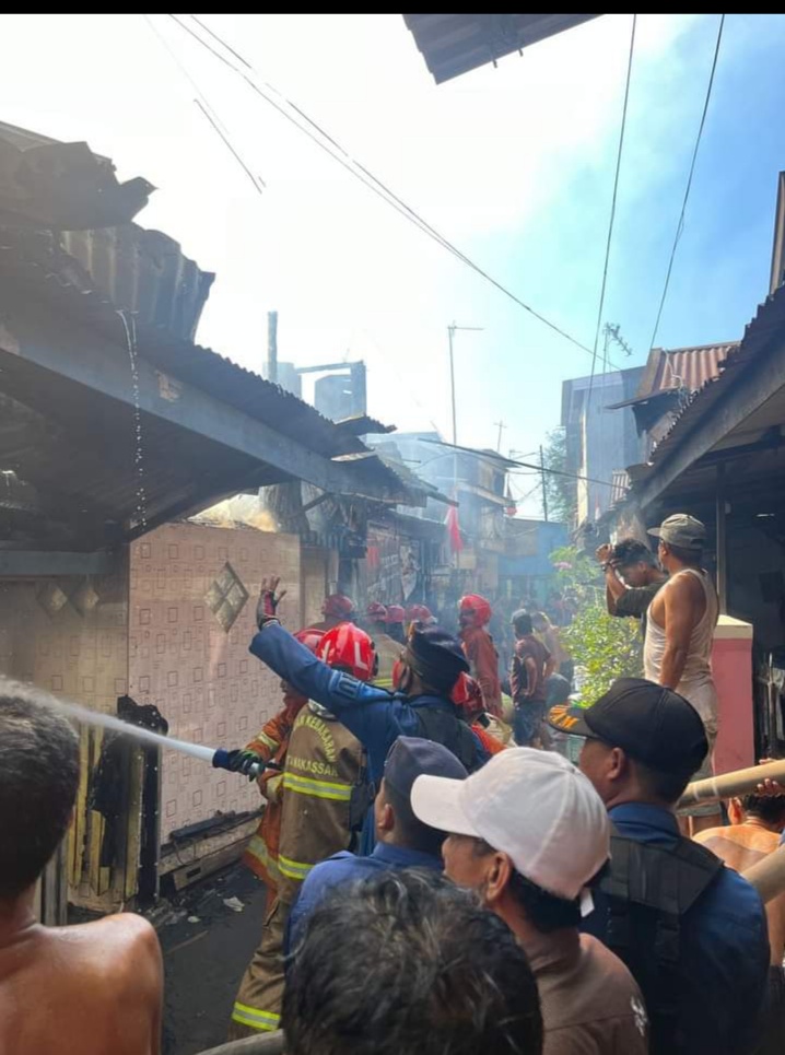 KEBAKARAN -- Petugas pemadam kebakaran Kota Makassar bersama warga memadamkan api di rumah warga yang terbakar di Jalan Dg Regge. 