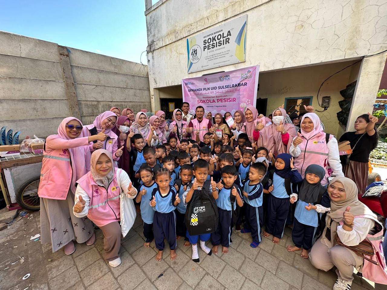 FOTO BERSAMA -- Para murid Sokola Bahari foto bersama dengan Srikandi PLN, perwakilan PLN UID Sulselrabar, dan YBM PLN di depan gedung sekolah mereka. 