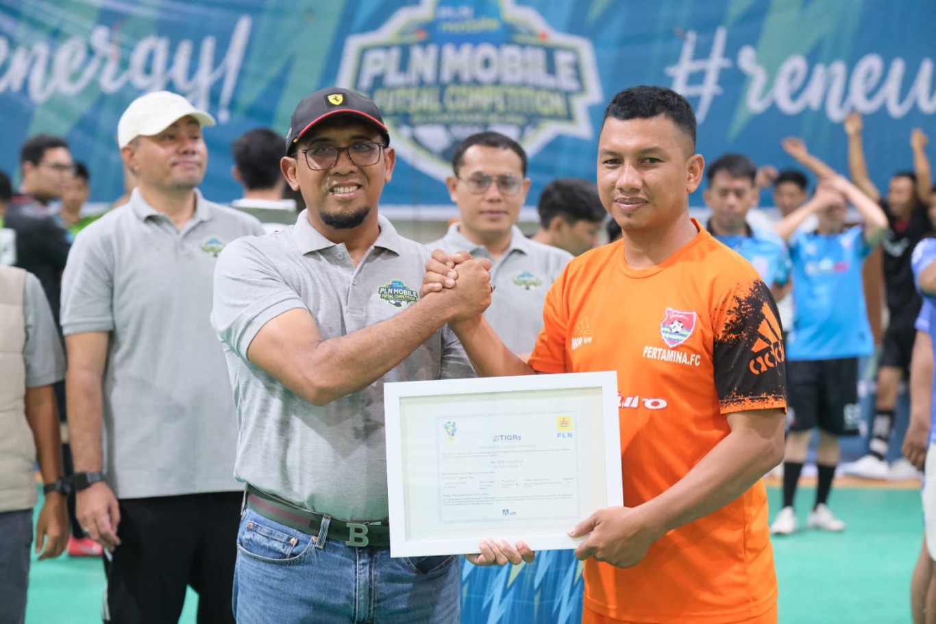 SIMBOLIS -- GM PLN UID Sulselrabar, Budiono (kiri) saat memberikan secara simbolis Renewable Energy Certificate kepada salah seorang  perwakilan tim futsal Pertamina FC dalam PLN Mobile Futsal Competition 2024. 