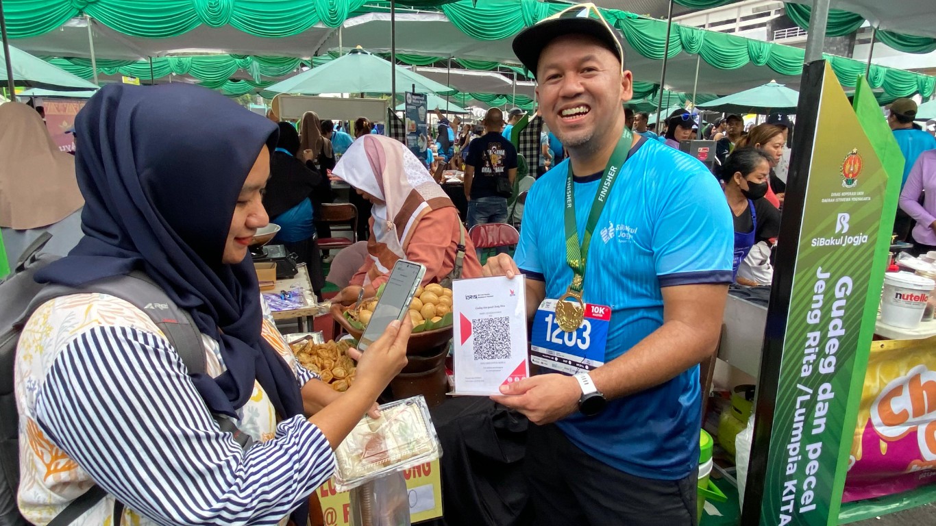 Direktur Finance & Strategy BSI Ade Cahyo Nugroho (kanan) saat melayani translaksi pembayaran QRIS pengunjung pada gelaran acara Sibakul Jogja Sport Fest 2024 di salah satu tenant UMKM yang berlokasi di Stadion Mandala Krida DIY, Minggu (1/9).