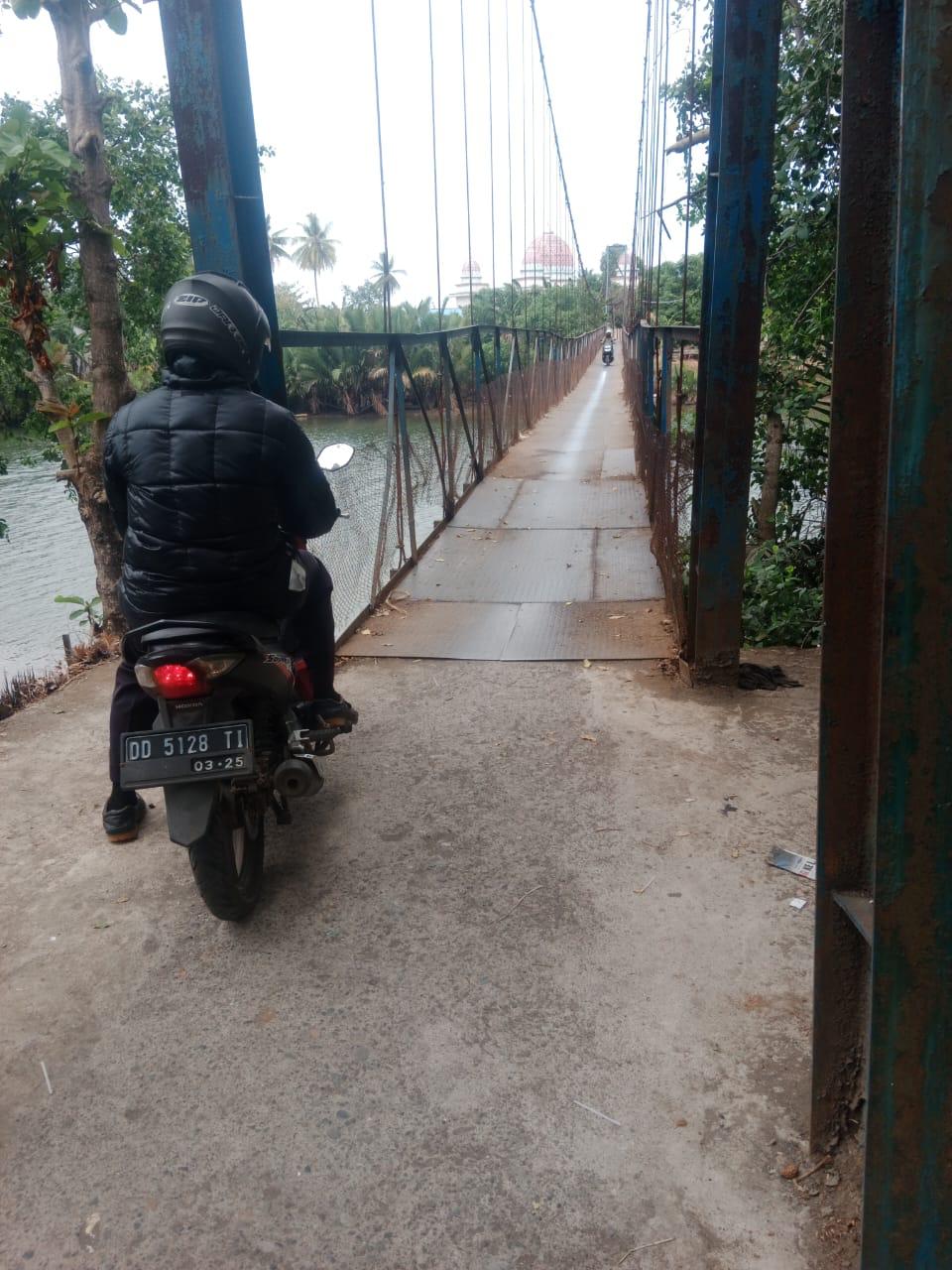 MENYEBERANG -- Seorang warga dengan mengendari sepeda motor akan menyeberangi jembatan penghubung Kelurahan Baju Bodoa dan Kelurahan Pallantikang, Kecamatan Maros Baru yang baru selesai dibenahi.
