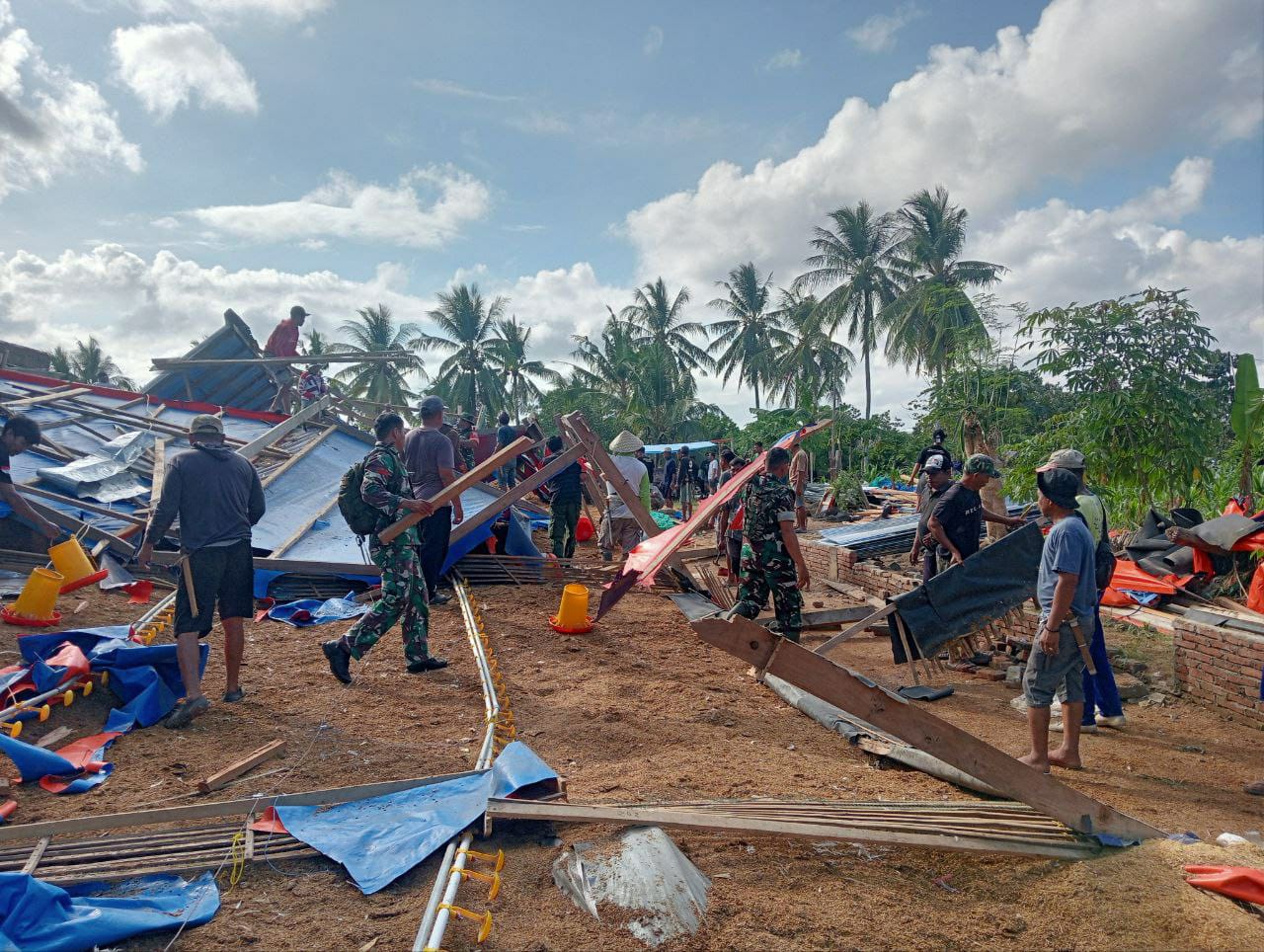 GOTONG ROYONG -- Aparat TNI bergotong royong membantu membersihkan puing-puing rumah dan kandang yang roboh akibat hujan deras disertai angin kencang pada Senin (23/9) lalu.
