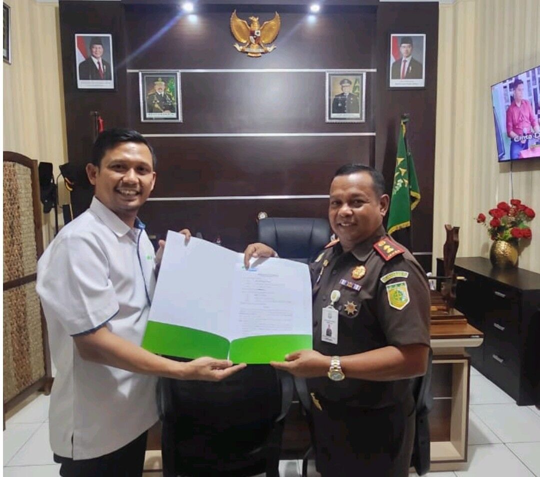 KERJA SAMA -- Kepala BPJS Ketenagakerjaan Cabang Palopo, Haryanjas Pasang Kamase bersama Kepala Kejari Enrekang, Padeli, S.H., M.Hum., menunjukkan naskah kerja sama yang telah ditandatangani kedua belah pihak.