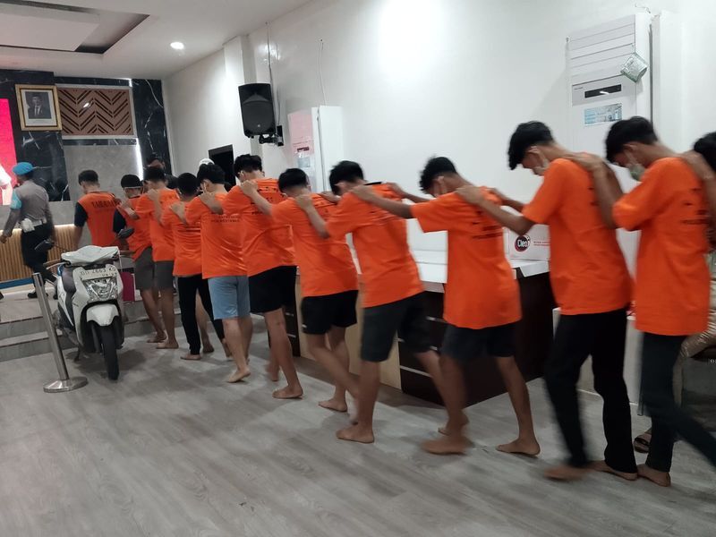 GENG MOTOR -- Para pelaku kelompok geng motor saat digiring petugas ke ruang pemeriksaan di Mapaolrestabes Makassar. Mereka berbaris dengan mengenakan baju orange. 
