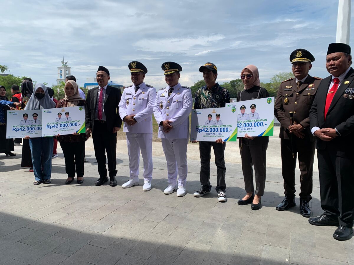 SANTUNAN -- Bupati Luwu, H Patahudding (empat dari kiri) didampingi wakil bupati dan Kepala BPJS Ketenagakerjaan Cabang Palopo, Haryanjas Pasang Kamase (tiga dari kiri) foto bersama para ahli waris Non-ASN dan anggota Korpri beserta unsur Forkopimda usai menyerahkan santunan JKM.