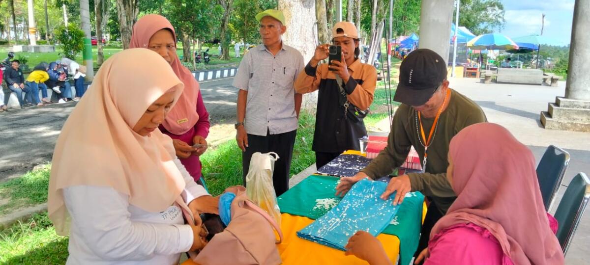 Warga menyaksikan batik ciprat yang dibuat para penyandang disabilitas dalam pameran mini di Taman Kota Masamba, Jumat (14/11/2025).