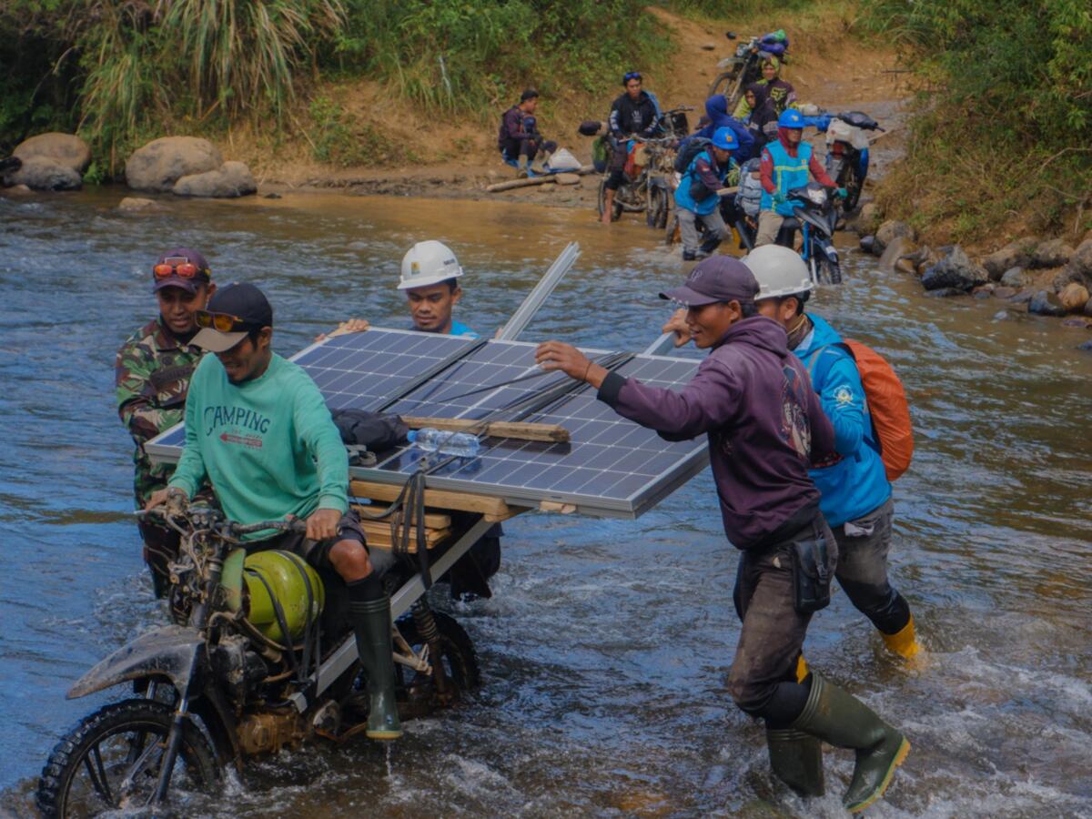 PANEL SURYA -- Petugas PLN bersama warga bahu-membahu membawa panel surya melintasi sungai. Upaya ini menjadi bagian dari perjalanan Program Listrik Desa (Lisdes) melalui SuperSUN dalam menghadirkan akses listrik bagi warga di Kecamatan Seko, Luwu Utara, Sulawesi Selatan. 