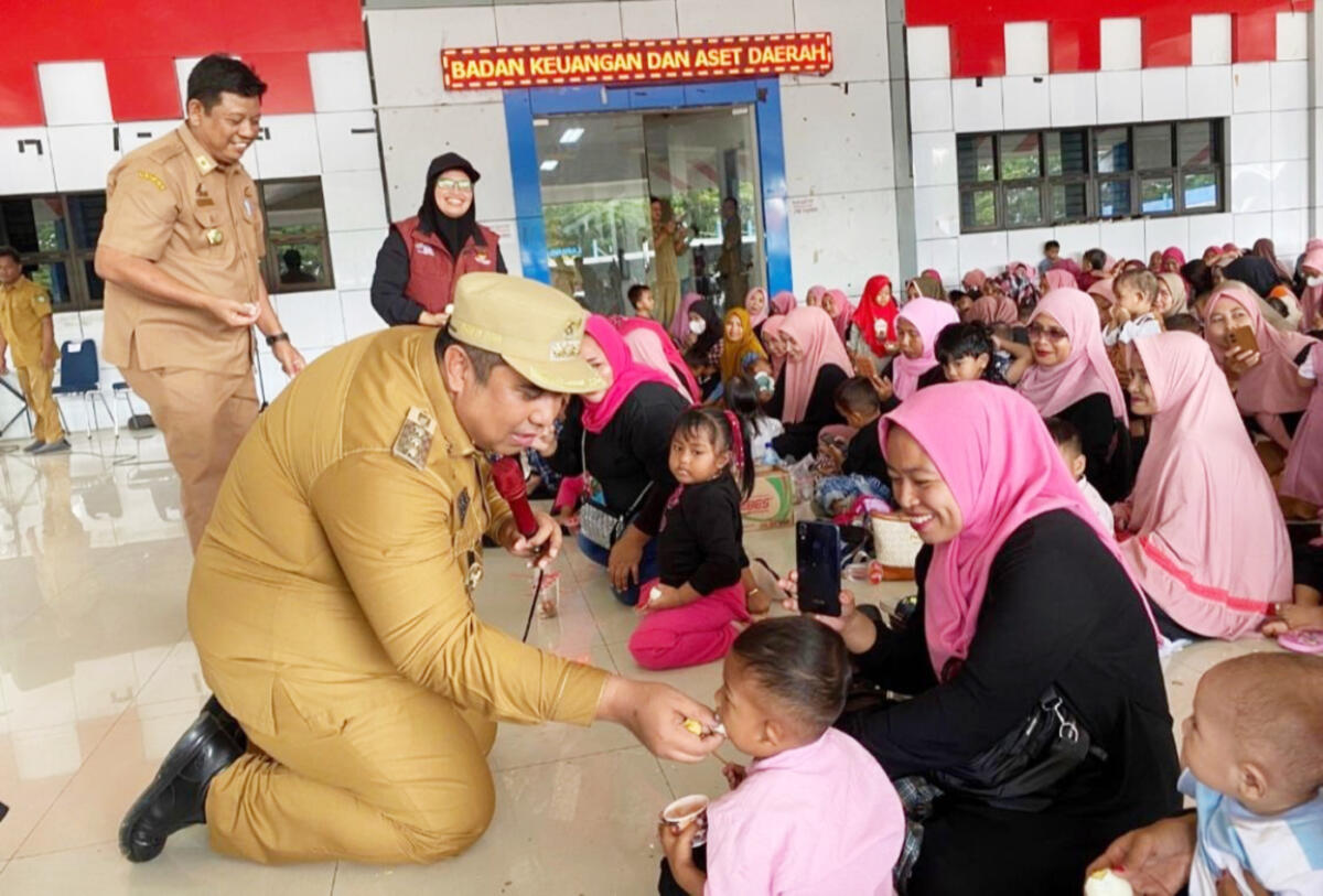MENYUAPI -- Bupati Maros, Chaidir Syam, menyuapi salah seorang anak yang turut hadir.bersama orangtuanya dalam kegiatan ini.
