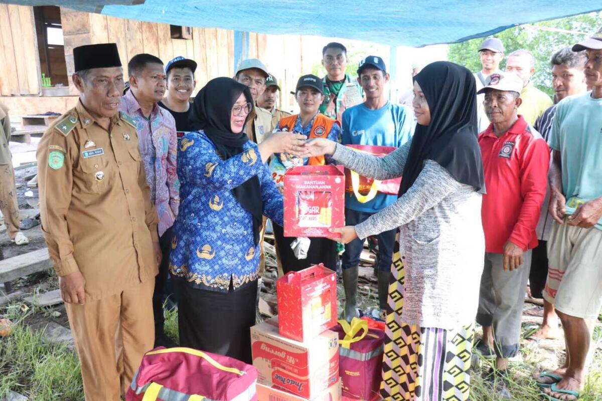 BERBAGI -- Wakil Bupati Luwu Timur, Hj. Puspawati Husler melewati jalan sempit di antara empang warga mengunjungi dan menyalurkan bantuan kepada para korban bencana angin kencang yang melanda Kecamatan Angkona, Senin (1/12).