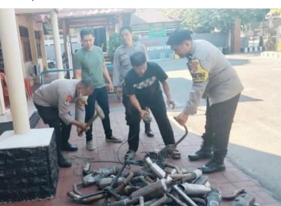 MUSNAHKAN -- Personel Polsek Makassar memusnahkan puluhan knalpot brong di halaman Mapolsek Makassar, 
